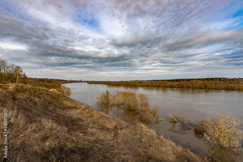 early spring flood, high water in the countryside, river overflowing its banks, trees in the water, flooded banks, environmental pollution, ecology © Sergei