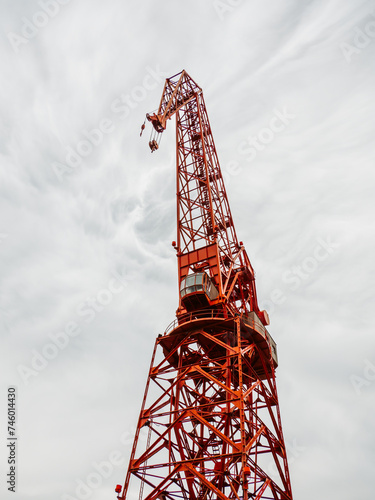 Red construction crane against a cloudy sky backdrop photo