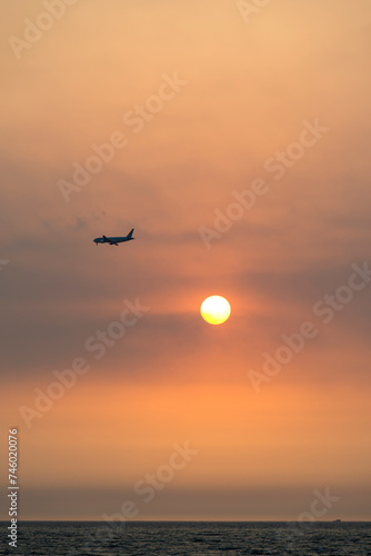 View of the sunset with a flying airplane