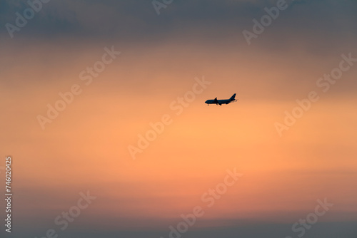 View of the sunset with a flying airplane