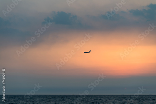 View of the sunset with a flying airplane