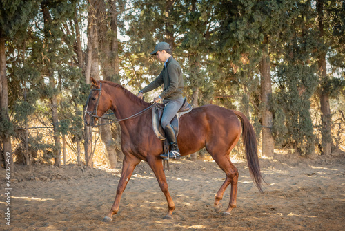 chico joven adolescente con gorra montando a caballo 
