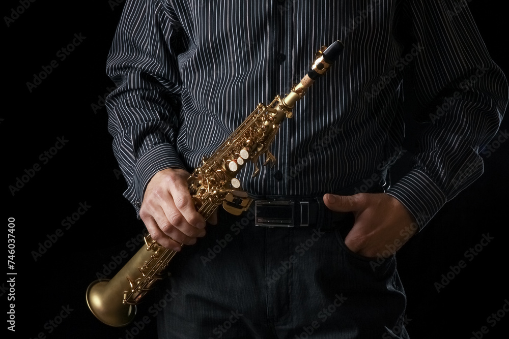 Naklejka premium soprano saxophone in the hands of a guy on a black background
