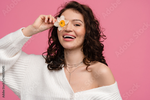 woman on pink background isolated in white knitted sweater holding flower spring summer trend fashion