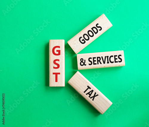 GST - Goods and Services Tax symbol. Concept word GST on wooden blocks. Beautiful green background. Business and GST concept. Copy space.