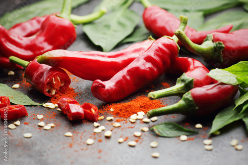 Fresh red chilli pepper spice with leaves of a plant on dark black background, closeup, indian or mexican food ingredients, asian cuisine concept photo