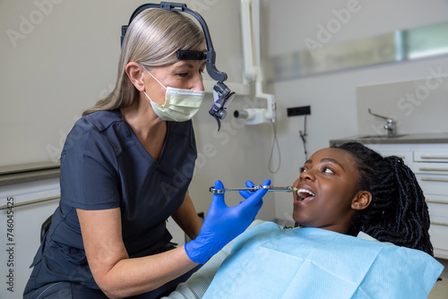 Dentist checking teeth of patient woman sitting in medical center