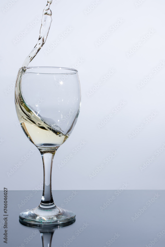 Splashes of light wine in a glass on a white background Splashes of light wine in a glass on a white background