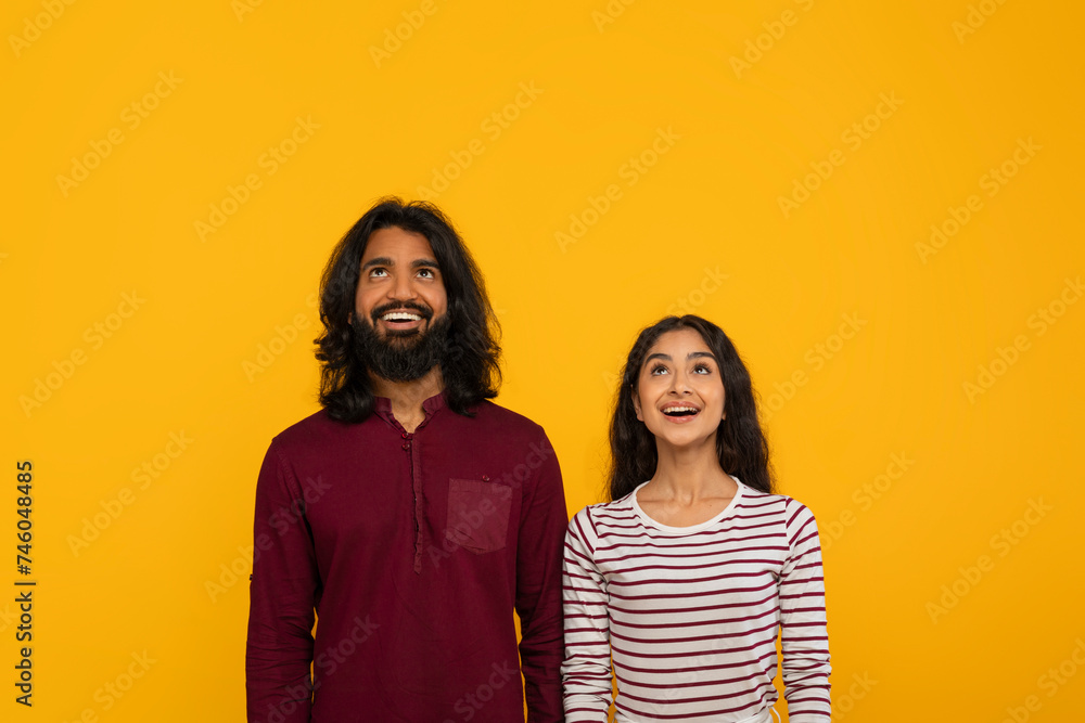 Curious young indian man and woman looking at copy space Curious young indian man and woman looking at copy space