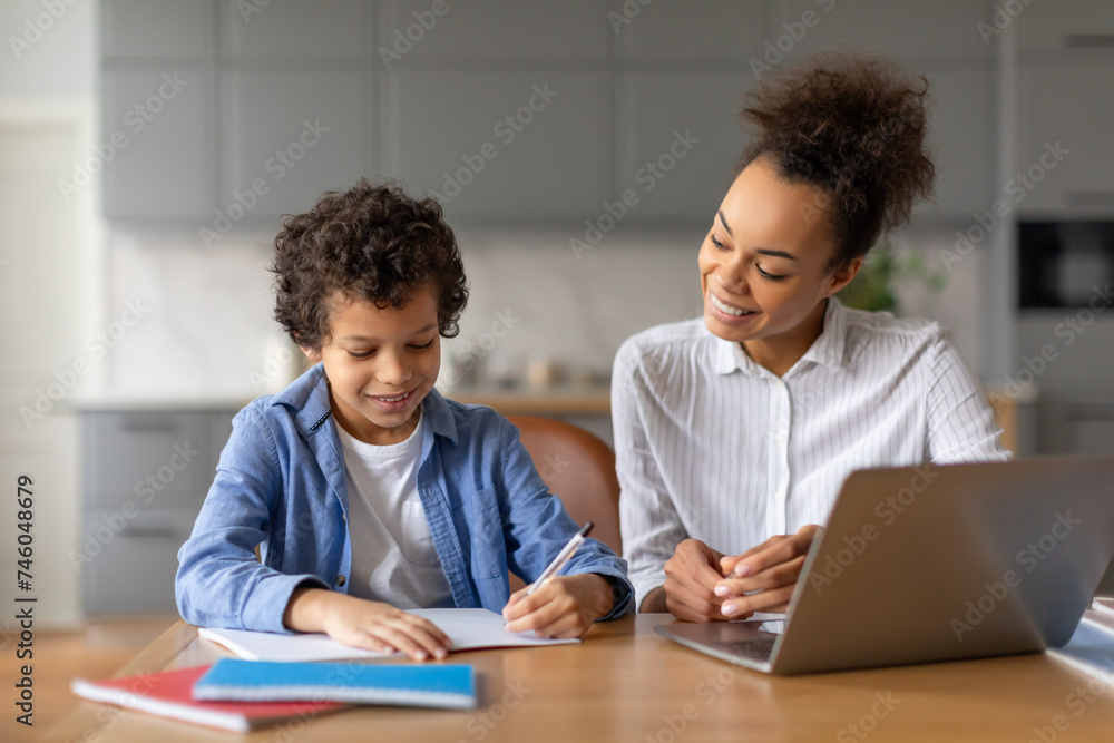 Black mother helps her son with homework at kitchen table Black mother helps her son with homework at kitchen table