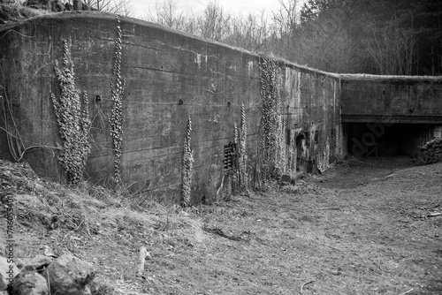 Poniemiecki bunkier - widoczna ściana z wejściem i widoczną strzelnicą na ciężki karabin maszynowy, który je osłaniał