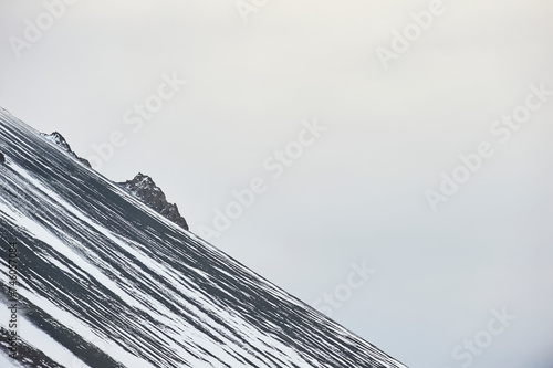 Diagonal snow patterns adorn the slopes of Hafnarfjall mountain near Borgarnes against a grey sky (region of Vesturland, Iceland) photo