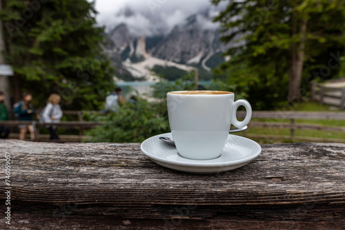 A cup of Italian cappuccino with Lake Pragser Wildsee in the background