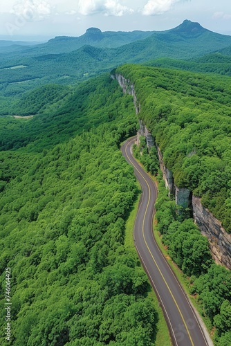 Winding road cutting through a lush green mountain landscape.
