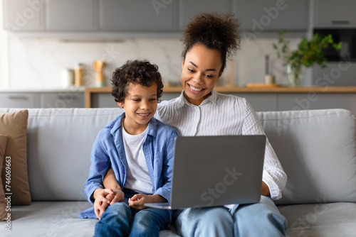 Black mother and son sharing moment with laptop at home