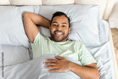 Positive young african american man laying in bed