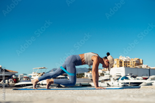 a girl in sportswear using a fitness elastic band to perform exercises that strain her muscles. The girl keeps in shape. Healthy lifestyle concept. Horizontal shot