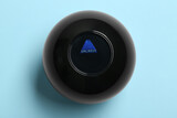 Magic eight ball with prediction Unlikely on light blue background, top view