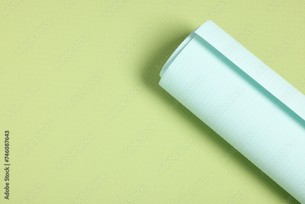 One light turquoise wallpaper roll on green sample, top view. Space for text One light turquoise wallpaper roll on green sample, top view. Space for text