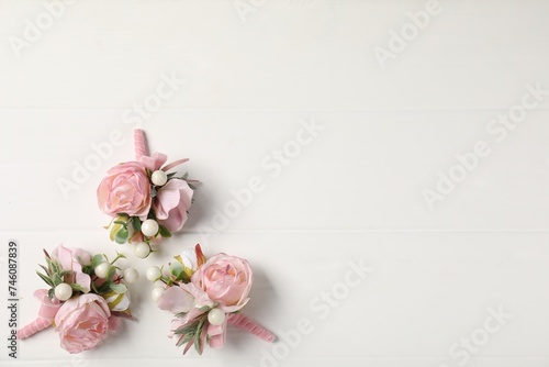 Beautiful boutonnieres on white background, flat lay. Space for text