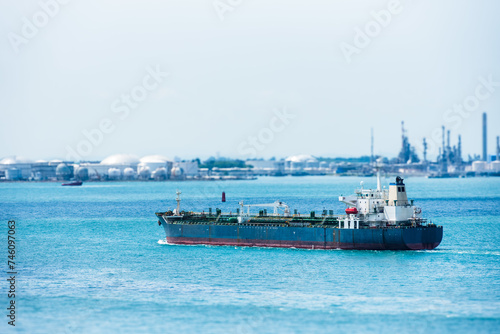 Oil tanker ship sailing through calm  blue waters inside sea port in Singapore.