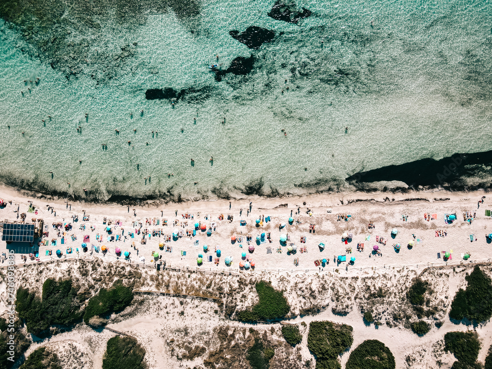 Aerial view of sandy beach with colorful umbrellas, unrecognizable people, sea coast with transparent blue water at sunny day in summer. Travel in Mallorca, Balearic islands, Spain. Top view. Tropical