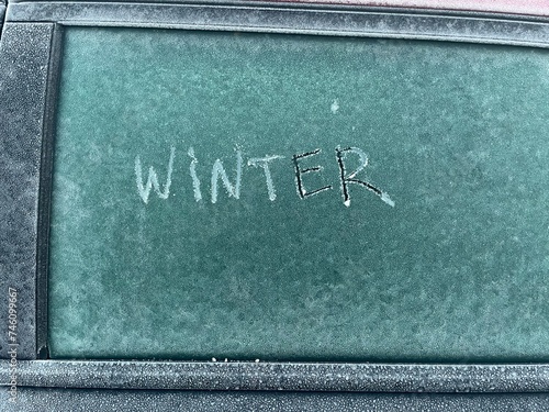 The word winter written in the frozen snow, covering the window of a car