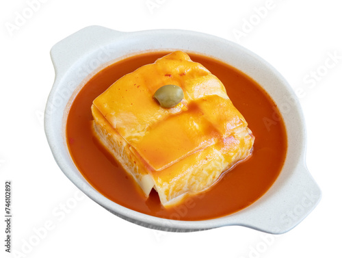 Traditional Portuguese Francesinha with sausage and meat, melted cheese, drizzled with beer sauce and olive. Close-up of plate on a white background.