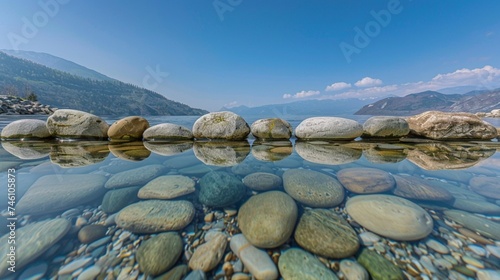 Reflective harmony: Smooth stones arranged in perfect balance, mirroring the clear sky above in a serene pool of water.