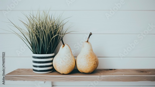 a couple of pears sitting on top of a wooden table next to a potted plant on top of a wooden shelf. photo