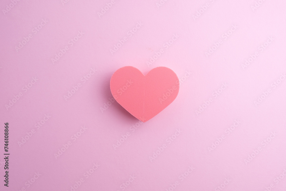 Beauty blender in the shape of a heart on a colored background. Bright sponges for cosmetics. Makeup products. Beauty concept. Place for text