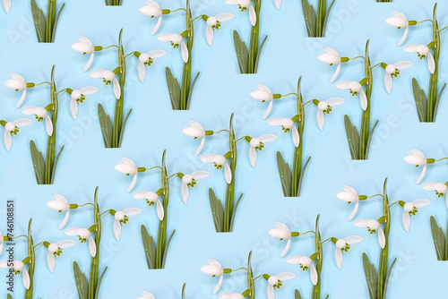 Pattern made with snowdrops and snowdrop leaves on bright blue background. Creative minimal art. Flat lay. Copy space. Minimal composition. Minimal wallpaper.