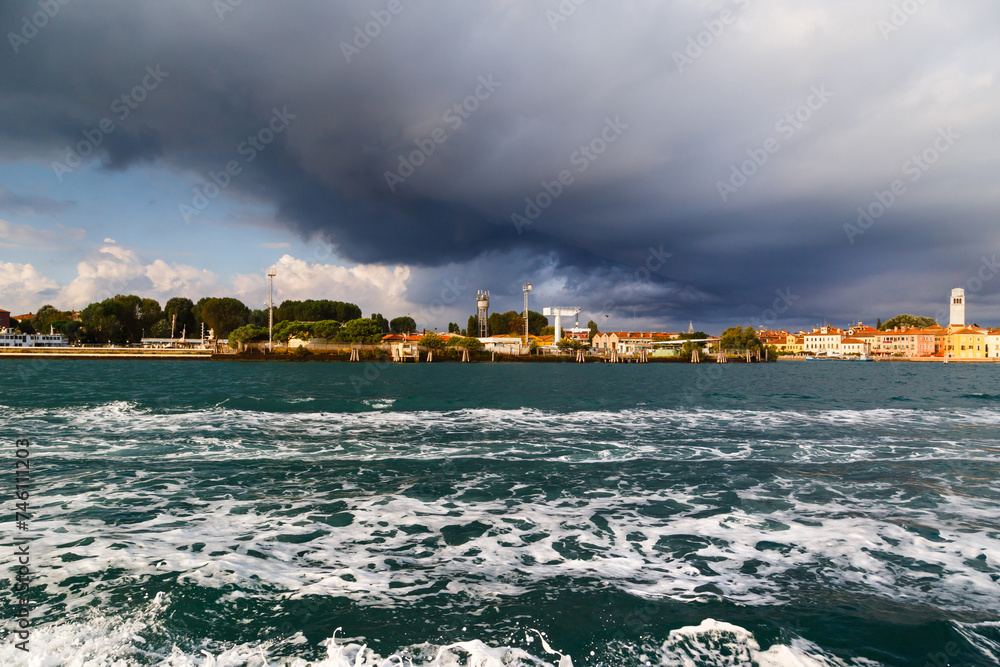 Obraz premium Sant'Elena and San Pietro di Castello island at extreme east end of sestiere of Castello in Venice, Italy. View from Venetian lagoon in stormy weather with dark cloudy sky in background