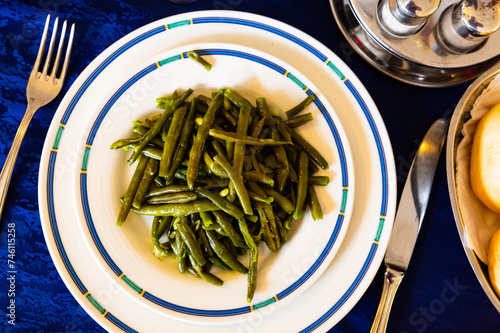Delicious vegetable garnish of stewed green beans on white plate photo