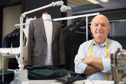 Portrait of an accomplished positive tailor with crossed arms in his workshop