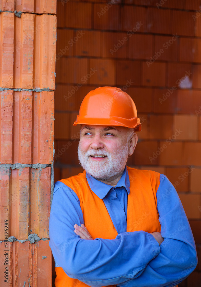 Construction worker in safety vest and hard hat. Smiling architect builder in protective helmet with crossed arms. Professional foreman, craftsman on construction site. Building and home renovation. Construction worker in safety vest and hard hat. Smiling architect builder in protective helmet with crossed arms. Professional foreman, craftsman on construction site. Building and home renovation.
