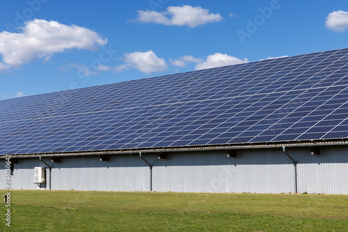 Halle mit Photovoltaik-Anlage, Solarzellen auf dem Dach in einem Gewerbegebiet in Niebüll, Schleswig-Holstein. An der Wand eine Wärmepumpe.