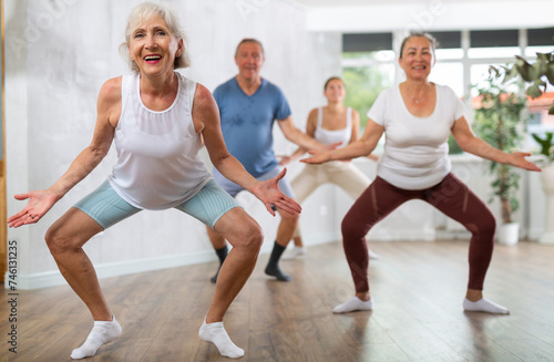 Group of sports people of different ages perform dance moves in fitness studio