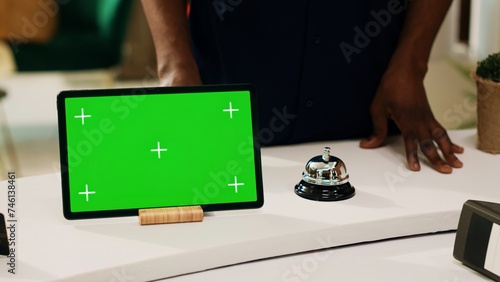 Fotografie Tourist asking about greenscreen display, pointing at digital tablet on reception front desk in hotel lobby