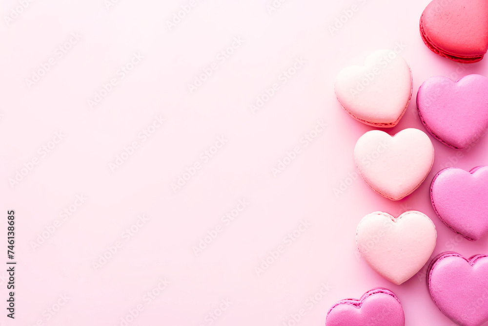 A collection of heart-shaped cookies neatly arranged on a pink background. Cookies of different sizes and decorated with colorful icing. Some of the cookies have sprinkles that 