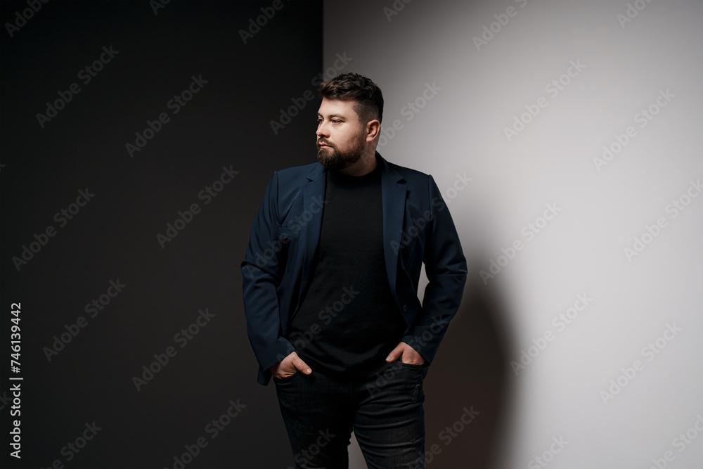 A confident, bearded man stands with his hands on his hips, dressed in a sleek, modern blazer A confident, bearded man stands with his hands on his hips, dressed in a sleek, modern blazer