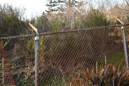 Rusted chain-link fence with barbed wire brackets, no barbed wire.