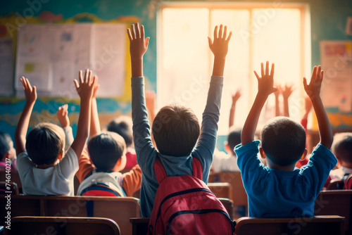 Classroom Curiosity: A captivating scene unfolds as children, seen from the back, enthusiastically raise their hands in the classroom to participate, learn, and satisfy their boundless curiosity © Mr. Bolota