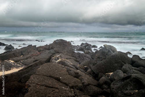Long exposure with some iguanas resting on the volcanic rocks of a beach. Isabela Island, Galapagos.