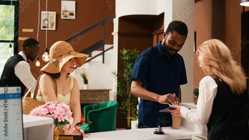 Photography Hotel guests checking in at reception, signing electronic documents on tablet