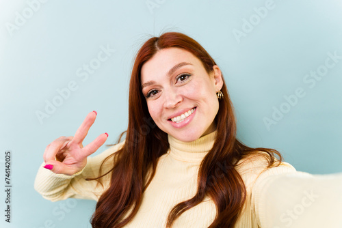 Gorgeous redhead woman taking a selfie making the peace sign