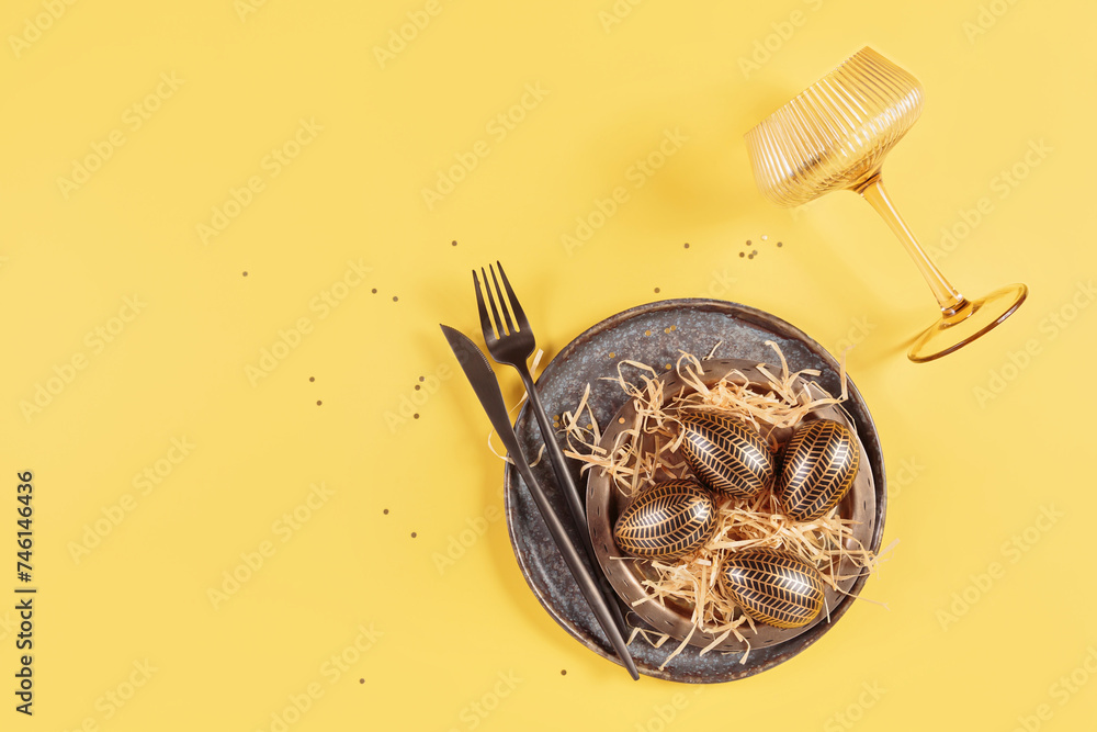 Fototapeta premium Table place setting and festive easter decor on yellow background. Happy easter greeting or invitation card. Top view, flat lay, copy space for text
