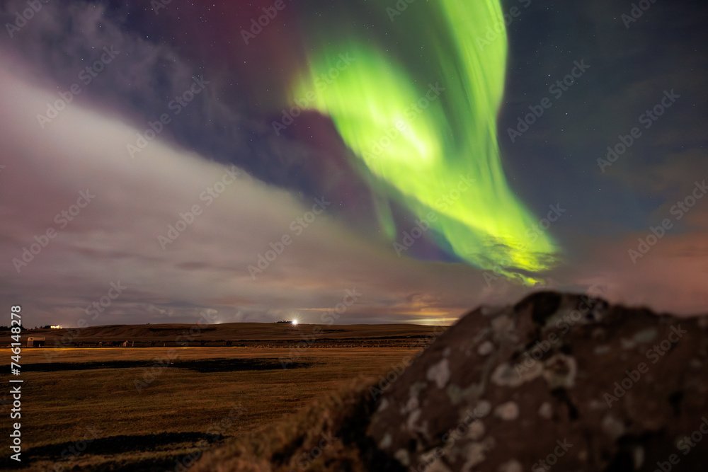 Icelandic highlands with northern lights are visible. Amazing scenery created by aurora borealis under sky full of stars. Stunning natural event with vibrant colors and snow covered rocks.