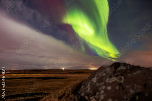 Icelandic highlands with northern lights are visible. Amazing scenery created by aurora borealis under sky full of stars. Stunning natural event with vibrant colors and snow covered rocks. © DC Studio