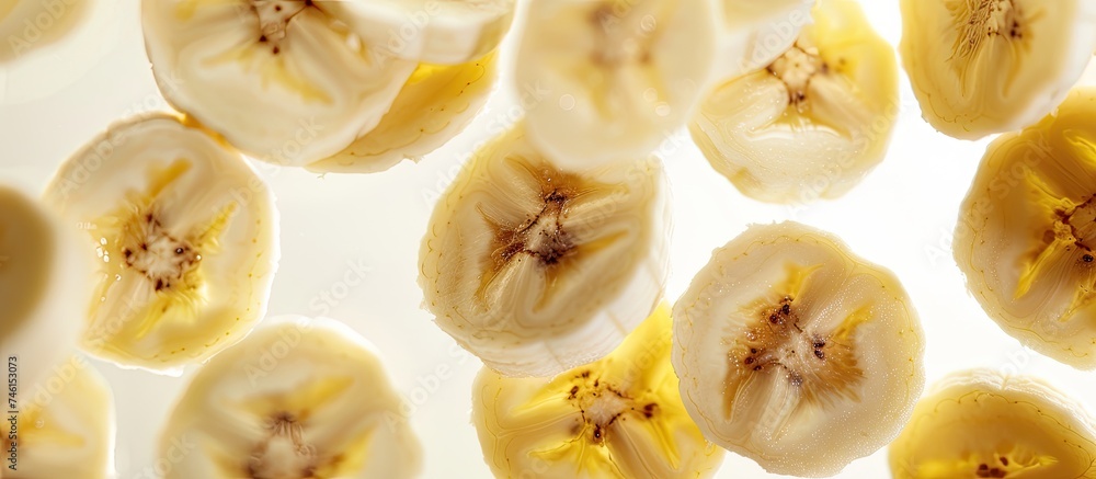 A bunch of bananas that have been cut in half, showing the cross-sections of the fruit. The banana slices are arranged on a white background with a shallow depth of field. A bunch of bananas that have been cut in half, showing the cross-sections of the fruit. The banana slices are arranged on a white background with a shallow depth of field.